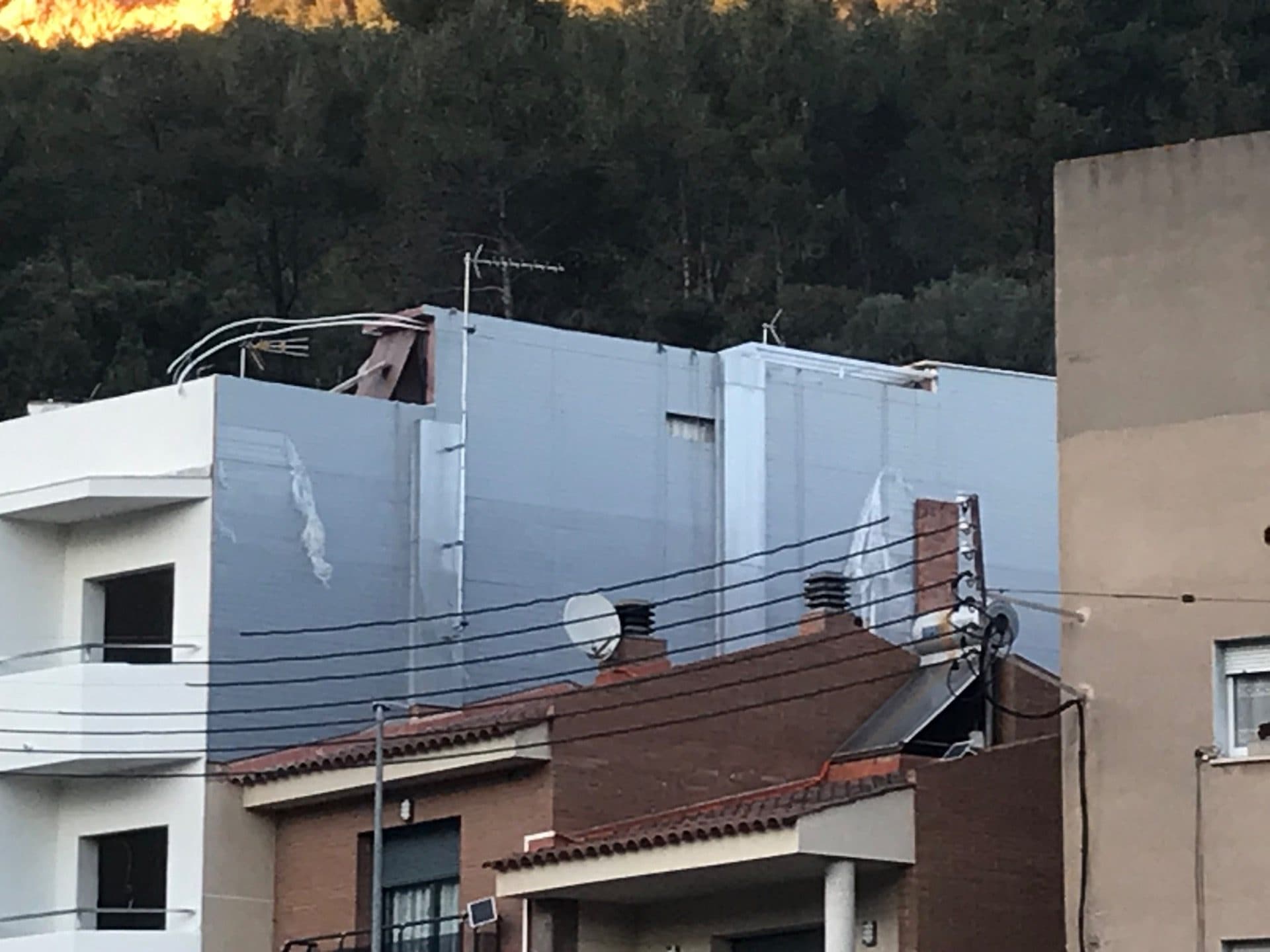 Fachada lateral terminada con el revestimiento de panel sándwich, vista desde la distancia al atardecer
