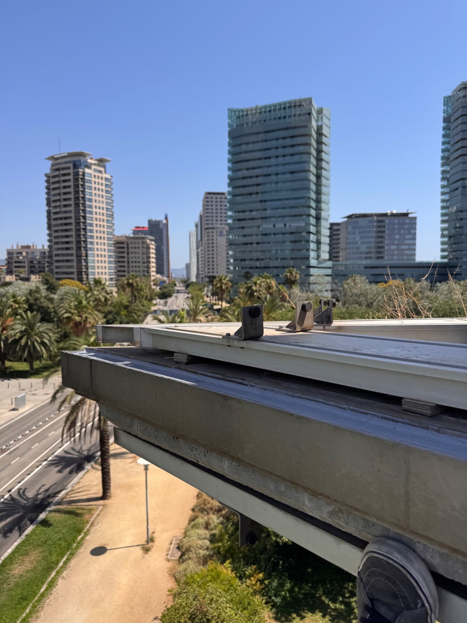 Detalle de una viga metálica con soportes sobre la cubierta de un edificio, con la ciudad al fondo